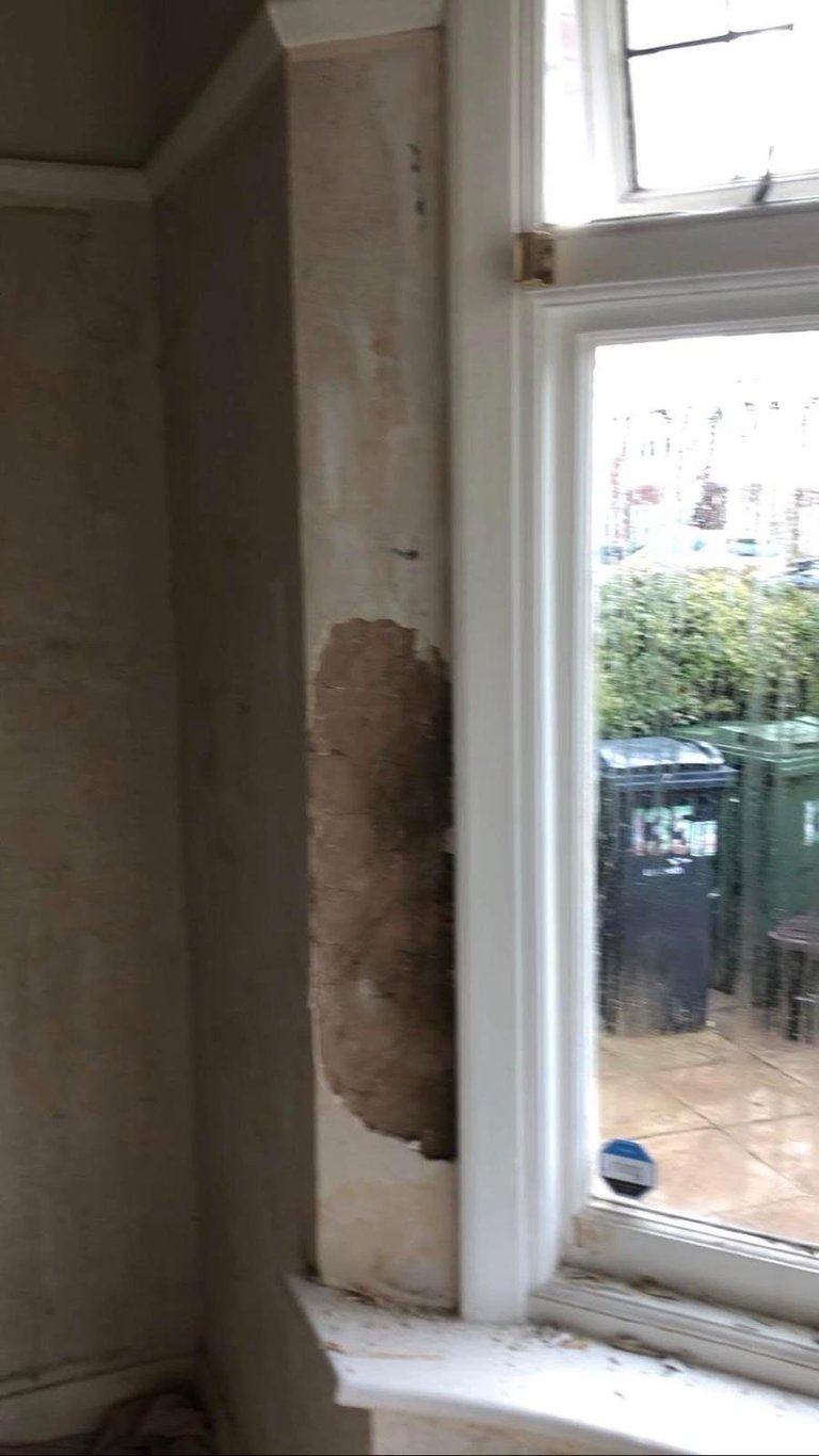 Cylindrical duct or pipe wrapped in brown insulation material next to a white framed glass door leading to outdoor patio