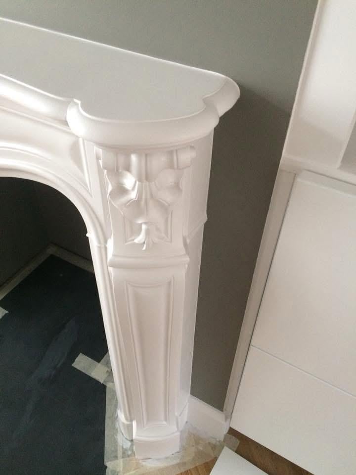 White decorative fireplace mantel with ornamental carved details
